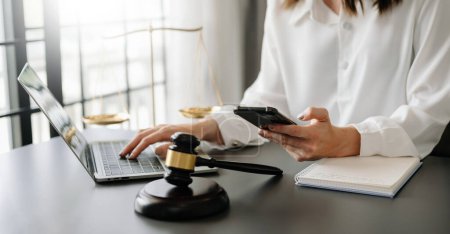 Foto de Justicia y derecho concept.female juez en un tribunal el mazo, trabajando con el teléfono inteligente y portátil - Imagen libre de derechos