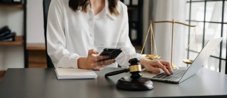 Photo for Justice and law concept.female judge in a courtroom  the gavel, working with smartphone and laptop - Royalty Free Image