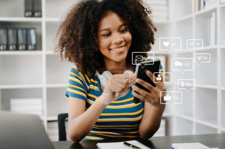 Téléchargez les photos : Femme africaine dactylographier smartphone avec ordinateur portable de médias sociaux et marketing concept d'écran d'icônes virtuelles - en image libre de droit