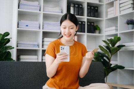 Téléchargez les photos : Asiatique femme en utilisant smartphone pour les paiements mobiles achats en ligne, omni canal, assis sur la table dans la lumière du matin - en image libre de droit