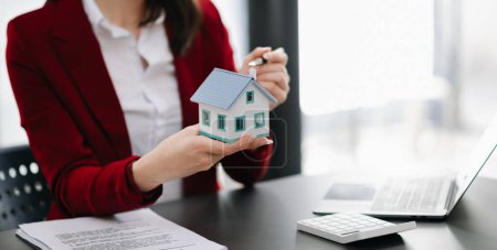 Téléchargez les photos : Saleswoman et modèle de maison, ordinateur portable et hypothèque Assurance et concepts immobiliers - en image libre de droit