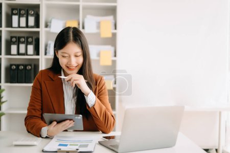 Téléchargez les photos : Jeune femme asiatique attrayante avec tablette et ordinateur portable travaillant de la maison, en regardant la caméra au bureau moderne - en image libre de droit