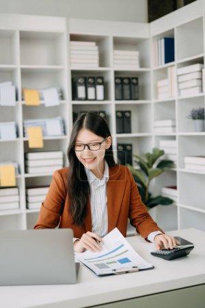 Téléchargez les photos : Asiatique femme d'affaires travaillant dans le bureau avec ordinateur portable et téléphone dans le bureau moderne - en image libre de droit