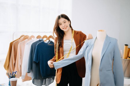 Foto de Mujer asiática diseñadora de moda revisando ropa mientras trabaja en sala de exposición de sastres - Imagen libre de derechos