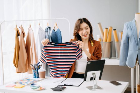 Foto de Mujer influencer asiática promoviendo y vendiendo ropa durante una videollamada en una tableta digital - Imagen libre de derechos