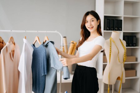 Téléchargez les photos : Asiatique Créateur de mode femme vérifier vêtements tout en travaillant dans le showroom tailleur - en image libre de droit