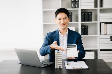 Photo for Young Asian real estate agent working in modern office - Royalty Free Image