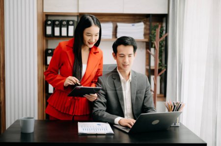 Téléchargez les photos : Deux hommes d'affaires asiatiques discutent de la stratégie de travail et de planification du projet d'investissement avec tablette PC et ordinateur portable dans un bureau moderne. - en image libre de droit