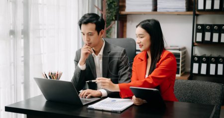Foto de Compañeros de negocios asiáticos usando laptop y tablet. Trabajo en equipo, equipo de marketing financiero, mientras está sentado en la moderna sala de oficina. - Imagen libre de derechos