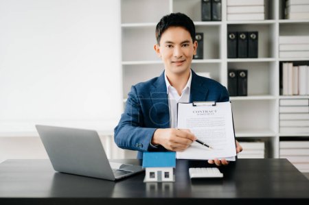 Téléchargez les photos : Jeune agent immobilier asiatique travaillant dans un bureau moderne - en image libre de droit