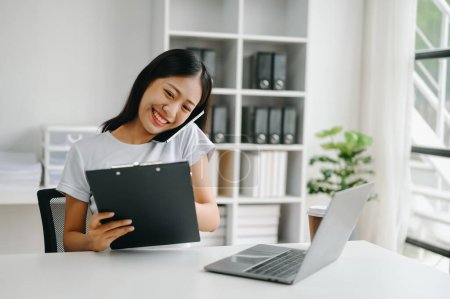 Téléchargez les photos : Heureuse femme d'affaires asiatique ont la joie de parler sur le smartphone, tablette et laptopon le bureau moderne - en image libre de droit