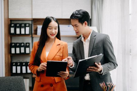 Foto de Dos empresarios asiáticos discuten el proyecto de inversión de trabajo y la estrategia de planificación con tablet PC en la oficina moderna. - Imagen libre de derechos