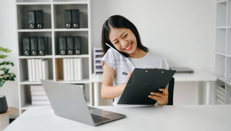 Téléchargez les photos : Heureuse femme d'affaires asiatique ont la joie de parler sur le smartphone, tablette et laptopon le bureau moderne - en image libre de droit