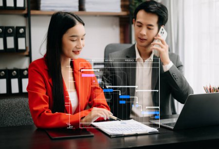 Photo for Business people updating tasks using Gantt chart scheduling virtual diagram. Colleagues working with laptop in modern office - Royalty Free Image