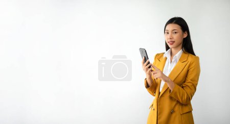 Foto de Foto de retrato de una joven hermosa mujer asiática sintiéndose feliz y sosteniendo el teléfono inteligente, sobre fondo blanco puede usar para publicidad o producto, presentando el concepto - Imagen libre de derechos