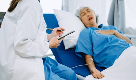 Téléchargez les photos : Médecin femme tenant la main masculine aînée sur le lit avec une solution saline à l'hôpital ou à la clinique - en image libre de droit