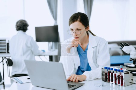 Photo for Two scientist or medical technician working, having a medical discuss meeting with an Asian senior female scientist supervisor in the laboratory with online reading, test samples - Royalty Free Image