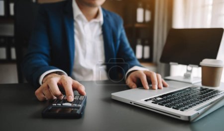 Photo for Women counting coins on calculator taking from the piggy bank. hand holding pen working on calculator to calculate on desk about cost at office - Royalty Free Image