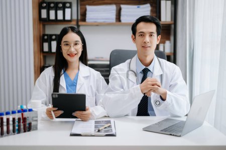 Photo for Medical technology network team meeting concept. Asian Doctor hand working with smart phone modern digital tablet and laptop computer with graphics chart interface, in the medical industr - Royalty Free Image