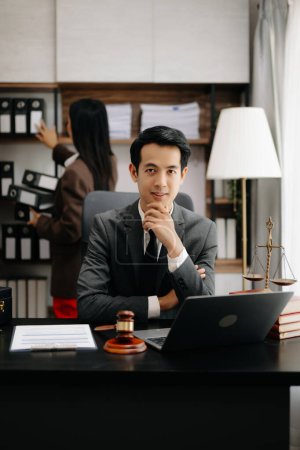 Téléchargez les photos : Un avocat asiatique travaillant avec un ordinateur portable dans un cabinet d'avocats. Concept de services juridiques et juridiques. Regardant la caméra - en image libre de droit