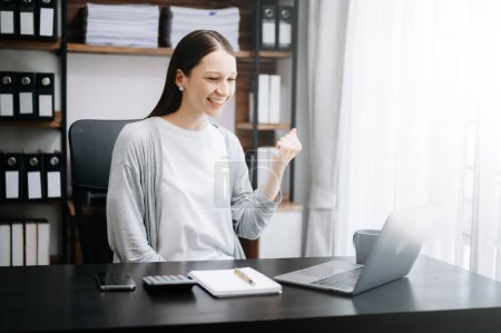 Téléchargez les photos : Souriant femme d'affaires caucasienne geste avec les mains bonheur tout en travaillant à table avec ordinateur portable au bureau - en image libre de droit