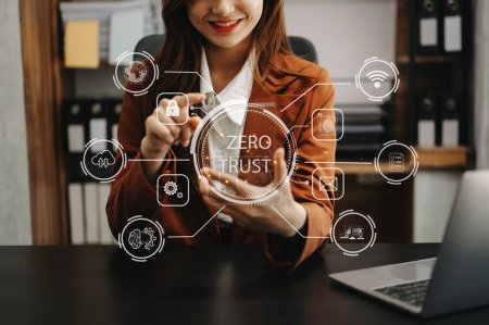 Foto de Concepto de seguridad de confianza cero Persona que usa computadora y tableta con icono de confianza cero en la pantalla virtual de la oficina de Data businesses.in - Imagen libre de derechos