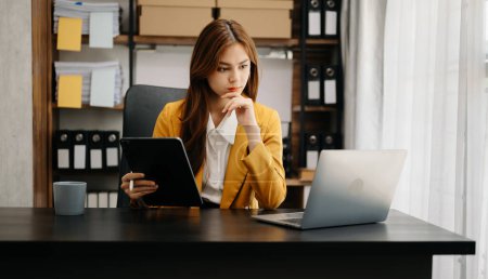 Téléchargez les photos : Expert d'affaires confiant attrayant souriant jeune femme asiatique tenant tablette numérique sur bureau dans le bureau créatif. - en image libre de droit