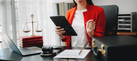 Téléchargez les photos : Image recadrée d'une femme d'affaires portant une veste rouge, travaillant au bureau avec un ordinateur portable et utilisant une tablette - en image libre de droit