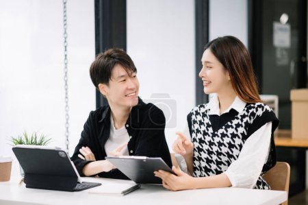 Téléchargez les photos : Homme d'affaires asiatique avec collègue femme utilisant tablette dans la salle de bureau moderne. Travail d'équipe, équipe de marketing financier - en image libre de droit