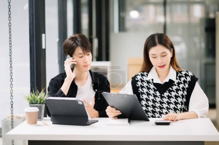 Foto de Hombre de negocios asiático con colega femenino usando tableta en la moderna sala de oficina. Trabajo en equipo, equipo de marketing financiero - Imagen libre de derechos