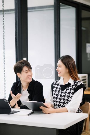 Photo for Two happy Asian businesspeople working together in office - Royalty Free Image