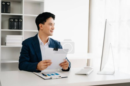 Photo for Young Asian businessman working with documents in modern office. Tax, report, accounting, statistics and analytical research concept - Royalty Free Image