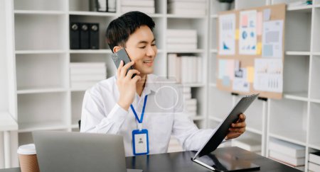 Téléchargez les photos : Heureux homme d'affaires asiatique ont la joie de parler sur le smartphone dans le bureau moderne - en image libre de droit