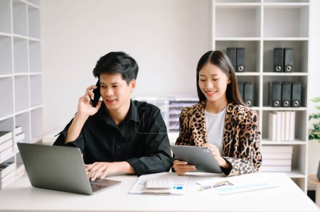 Téléchargez les photos : Deux hommes et femmes d'affaires asiatiques utilisant un ordinateur portable. Professionnels travaillant au bureau. - en image libre de droit