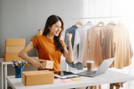 Photo for Fashion blogger concept, Young Asian woman selling clothes on video streaming.Startup small business SME, using  tablet and laptop taking receive and checking in office - Royalty Free Image