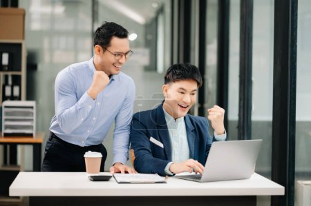 Téléchargez les photos : Deux hommes d'affaires asiatiques souriant assis ensemble dans un bureau moderne - en image libre de droit