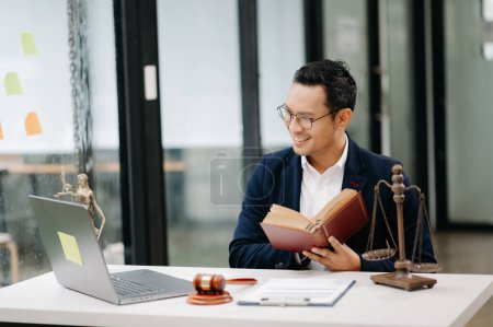 Foto de Abogado masculino leyendo libro con mazo en la mesa en la oficina moderna. justicia y derecho, concepto de abogado - Imagen libre de derechos