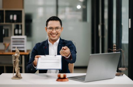 Foto de Concepto de justicia y derecho. Feliz asiático hombre abogado trabajando con portátil y documentos en la oficina - Imagen libre de derechos
