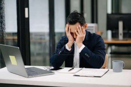 Téléchargez les photos : Un jeune homme d'affaires asiatique surmené se sent fatigué après une longue journée de travail. Syndrome de bureau - en image libre de droit