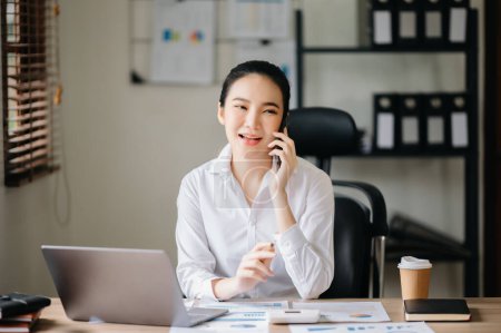 Foto de Negocios mujer asiática Hablando por teléfono mientras está sentado en la oficina moderna - Imagen libre de derechos
