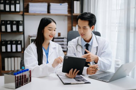 Foto de Concepto de reunión del equipo de tecnología médica. Médicos asiáticos trabajando en tableta digital con interfaz gráfica, en la industria médica - Imagen libre de derechos