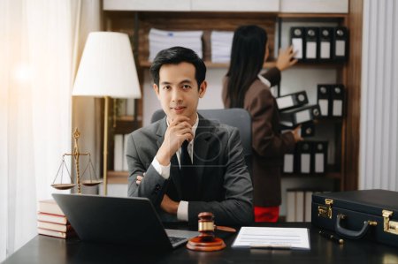 Téléchargez les photos : Un avocat asiatique travaillant avec un ordinateur portable dans un cabinet d'avocats. Concept de services juridiques et juridiques - en image libre de droit