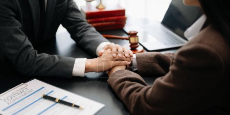 Photo for Business people compassionately holding hands and discussing contract papers with laptop and tablet at office room - Royalty Free Image