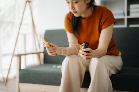 Téléchargez les photos : Jeune femme asiatique assise dans le canapé avec un grand nombre de pilules Femme déprimée veut se suicider par surdose de drogue, concept de dépression - en image libre de droit