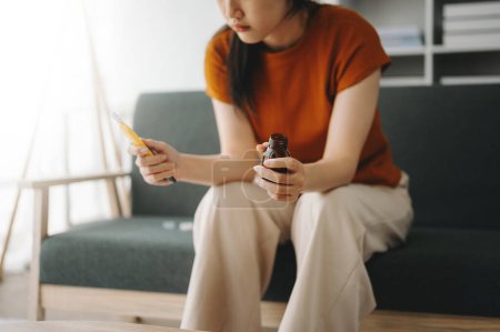Téléchargez les photos : Jeune femme asiatique assise dans le canapé avec un grand nombre de pilules Femme déprimée veut se suicider par surdose de drogue, concept de dépression. - en image libre de droit