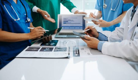 Téléchargez les photos : Équipe médicale ayant une réunion assise à une table et discutant d'un patient, travaillant en ligne et utilisant des ordinateurs dans l'industrie médicale ou à l'hôpital - en image libre de droit