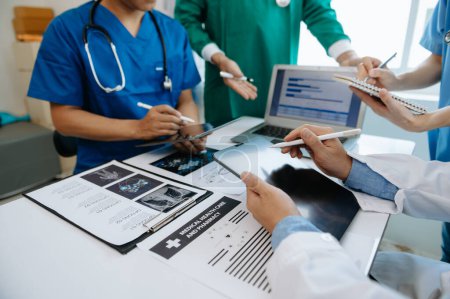 Téléchargez les photos : Équipe médicale ayant une réunion assise à une table et discutant d'un patient, travaillant en ligne et utilisant des ordinateurs dans l'industrie médicale ou à l'hôpital - en image libre de droit