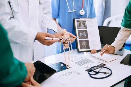 Téléchargez les photos : Équipe médicale en réunion avec des médecins en blouse blanche et en gommage chirurgical assis à une table pour discuter d'un patient travaillant en ligne à l'aide d'ordinateurs dans l'industrie médicale - en image libre de droit