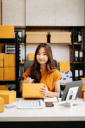 Photo for Startup small business SME, Asian woman entrepreneur checking online orders and preparing parcels for shipping - Royalty Free Image