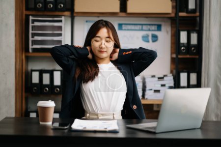 Photo for Overworked young Asian businesswoman office worker suffering from neck pain after had a long day at her office desk. office syndrome concept - Royalty Free Image